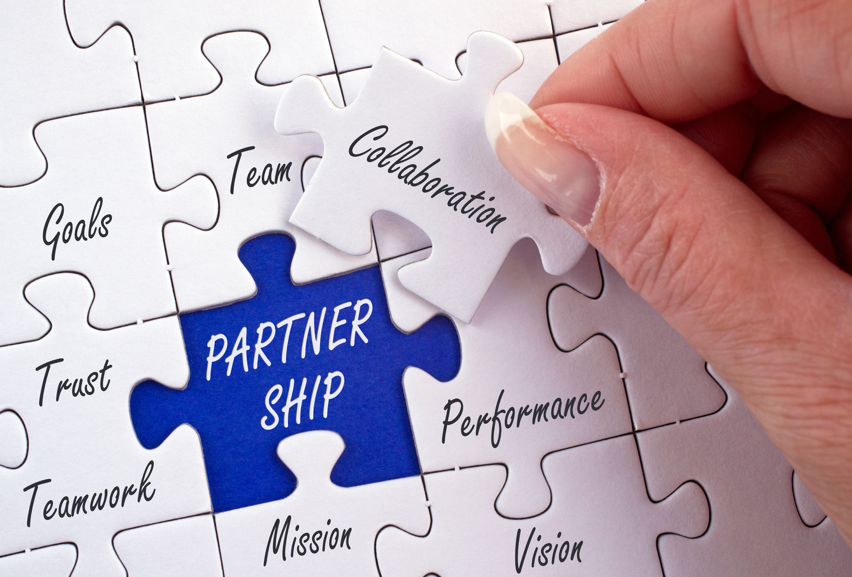 Image of a hand placing a missing jigsaw piece into the space for the word ‘partnership’ to complete the jigsaw.